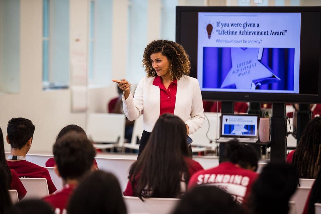 Christine Sylvain teaching in classroom with presentation slide