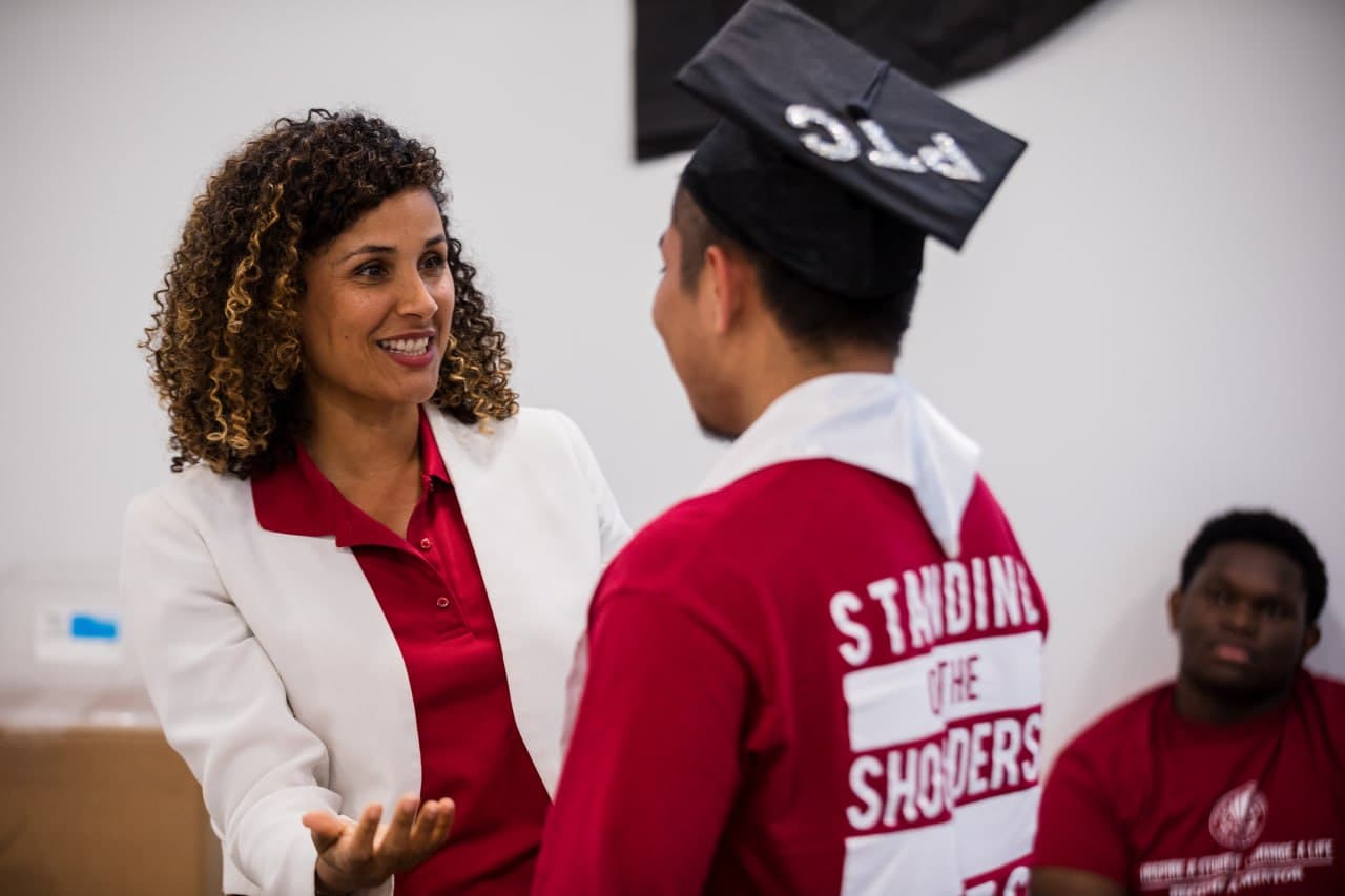 Christine Sylvain speaking with a graduate in cap and gown